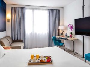 科尔内拉德罗布雷加特诺富特巴塞罗那科内拉酒店的酒店的客房 - 带一张床和一张带食品托盘的书桌