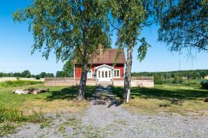 卡特琳娜霍尔姆Gård med egen sjö med bryggbåt, nyrenoverat!的前面有两棵树的红房子