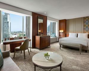 雅加达雅加达君悦酒店的配有一张床、一张桌子和一张桌子的酒店客房