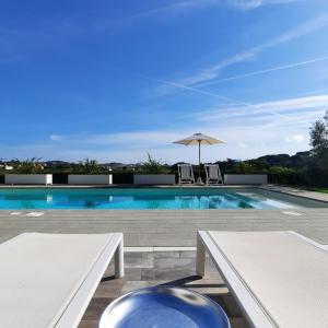 费拉约港La Suite con Piscina Privata的一个带两个白色长椅和遮阳伞的游泳池