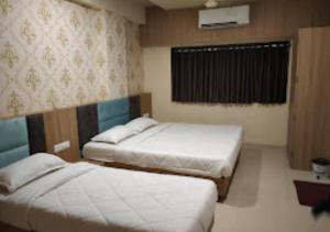 JālgaonHotel New Delhi darbar family restaurant Jalgaon的一间卧室设有两张床,其中设有窗户。