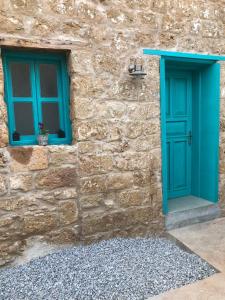 法马古斯塔Bella Casetta Guest House的一座石头建筑,设有蓝色的门和两扇窗户