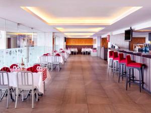 梭罗Grand Mercure Solo Baru的一间设有白色桌子和红色椅子的餐厅