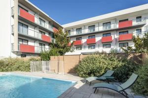 特里尼亚克Best Western Les Aureliades Saint Nazaire的公寓大楼前方设有游泳池