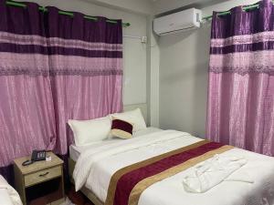 巴拉特布尔Hotel Kavya Inn的一间卧室配有两张床和紫色窗帘