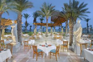 沙姆沙伊赫Jaz Fayrouz的餐厅拥有棕榈树和白色的桌椅