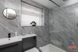 达特福德OnSiteStays - Stylish 4 BR House with Beautiful Outdoor Space, Wi-Fi & Smart TVs的一间带水槽、卫生间和镜子的浴室