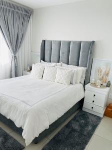 SandtonApollo one bedroom的卧室配有一张白色大床和灰色床头板