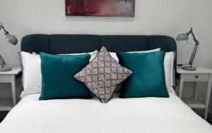 米查姆London Stunning Three Bedroom House的一张带绿色和白色枕头的床以及两盏灯