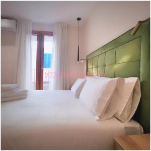 索列尔MOONTEN Boutique Stay的一间卧室配有一张白色大床和绿色床头板