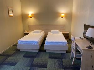 雷泽克内涅日克内可隆纳酒店的小型客房配有两张床铺、书桌和电脑。