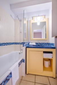 圣罗兰度瓦Résidence Pierre & Vacances Heliotel Marine的带浴缸、水槽和镜子的浴室
