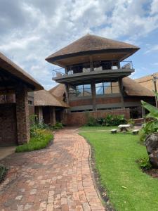 KingsmeadLovely safari room in Harare - 2181的一座带砖砌走道的屋顶大建筑