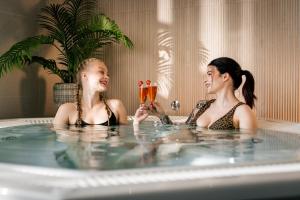 拉彭兰塔Hotelli Lähde的两个女孩在浴缸里拿着香槟