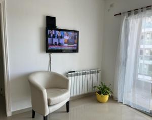 里奥夸尔托Departamento 6 piso con piscina, de 1 dormitorio的客厅配有椅子和墙上的电视