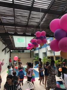 塔科拉迪Sosa Guest House的一群人站在一个游泳池周围,拿着粉红色的气球