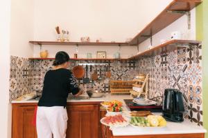 槟知Entire First Floor - Nguyên Tầng Trệt- Nhà Mơ Homestay Bến Tre的站在厨房准备食物的妇女