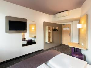 杜塞尔多夫B&B HOTEL Düsseldorf-Mitte的酒店客房设有一张床、一张书桌和一台电视机。