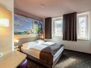 杜塞尔多夫B&B HOTEL Düsseldorf-Mitte的酒店客房设有一张床和两个窗户。