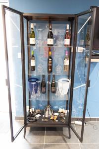 欧塞尔Le Domaine de la Clarté AUXERRE - VENOY的装满酒瓶和玻璃杯的玻璃柜