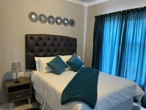 梅富根Mafikeng Boutique Lodge的一间卧室配有一张带蓝色窗帘的大床