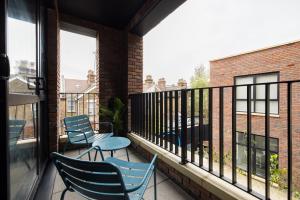 伦敦The Wembley Hideout - Stylish 2BDR Flat with Balcony的阳台配有桌椅和窗户。