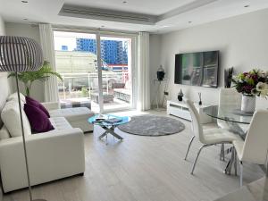 直布罗陀Marina Club - Luxury Apartment in Ocean Village with Parking的客厅配有白色家具和玻璃桌