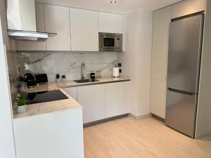 直布罗陀Marina Club - Luxury Apartment in Ocean Village with Parking的厨房配有白色橱柜和不锈钢冰箱