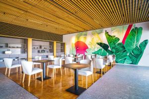 阿吉内金海滩Resort Cordial Santa Águeda & Perchel Beach Club的餐厅设有桌子和白色椅子,并装饰有壁画