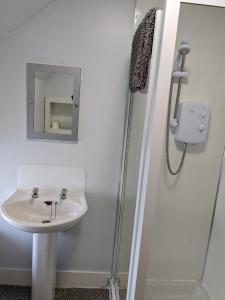 因弗鲁里Bennachie Lodge Hotel in Kemnay的白色的浴室设有水槽和淋浴。