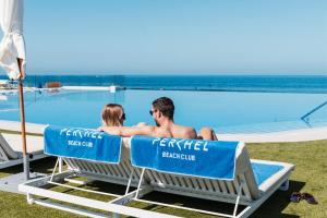 阿吉内金海滩Resort Cordial Santa Águeda & Perchel Beach Club的坐在游泳池旁椅子上的男女