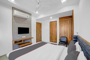 艾哈迈达巴德HOTEL TAPOVAN IN的一间卧室配有一张床、一台电视和一把椅子
