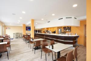 MonteHotel Arias Aeropuerto的一间带桌椅的餐厅和一间酒吧