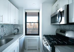 纽约Excellent 3 Bed 1 Bath In Mid East的厨房配有白色橱柜和炉灶烤箱。