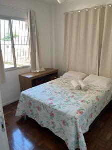 维多利亚Aloha aluguel para temporadas的一间卧室配有一张带鲜花毯子的床和窗户。