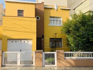 利马Peruvian House - Miraflores的黄色房子,有两个白色车库门