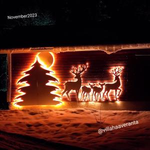 罗瓦涅米Villa Haaveranta - Cosy cabin by the lake的三个鹿站在一个壁炉前,上面有一棵圣诞树