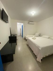 阿布拉奥Suite Grega 5- Centro da Vila Abrãao的一间白色卧室,配有两张床和电视