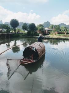 宁平Tam Coc Lotus Flower Homestay的两人在船上,水里挂着网