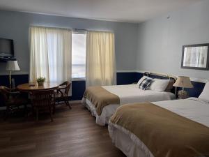 奇利瓦克Royal Hotel Chilliwack的酒店客房设有两张床、一张桌子和一个窗户。