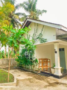 斯勒曼Homestay Kamar Tamu Selomartani 3的白色的小房子,有门廊和树
