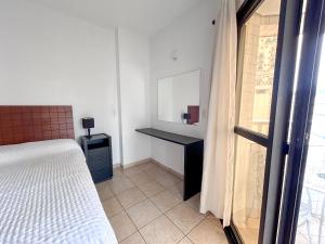 桑托斯Apartamento no Mercure - canal 3的一间卧室配有一张床、一张书桌和一个窗户。