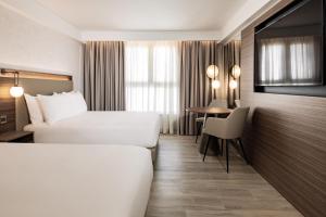 圣朱利安斯AC Hotel by Marriott St Julian's的酒店客房设有两张床和一张桌子。
