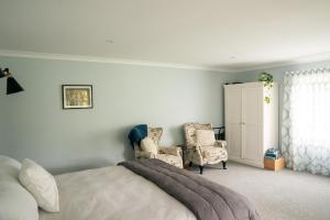 帕拉帕拉乌穆Birdsong Cottage的一间卧室配有一张床、两把椅子和一个橱柜