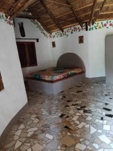 AbéméCampement Nyabinghi的一间卧室设有一张床,铺有石头地板。