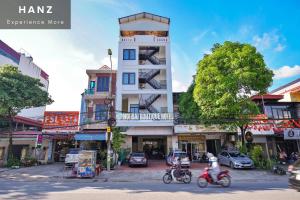 河内HANZ Noi Bai Airport Hotel的两个人骑摩托车在大楼前的街道上