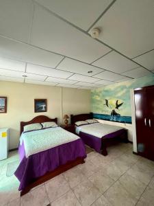 阿约拉港Nelyza's Suites & Adventure的一间卧室设有两张床,天花板上绘有绘画作品
