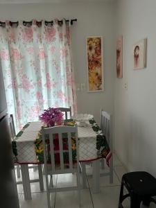 伊塔佩马Residencial Lara的餐桌,两把椅子和一张鲜花桌子