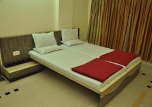 BhusāwalHotel Premier - Hotel in Saket Society Bhusawal的一间卧室配有一张带红色和白色棉被的床