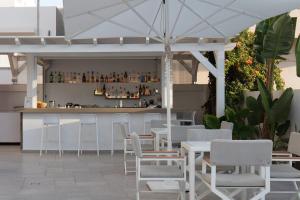 罗希姆诺阿瑞斯提酒店的餐厅设有酒吧,配有白色的桌椅